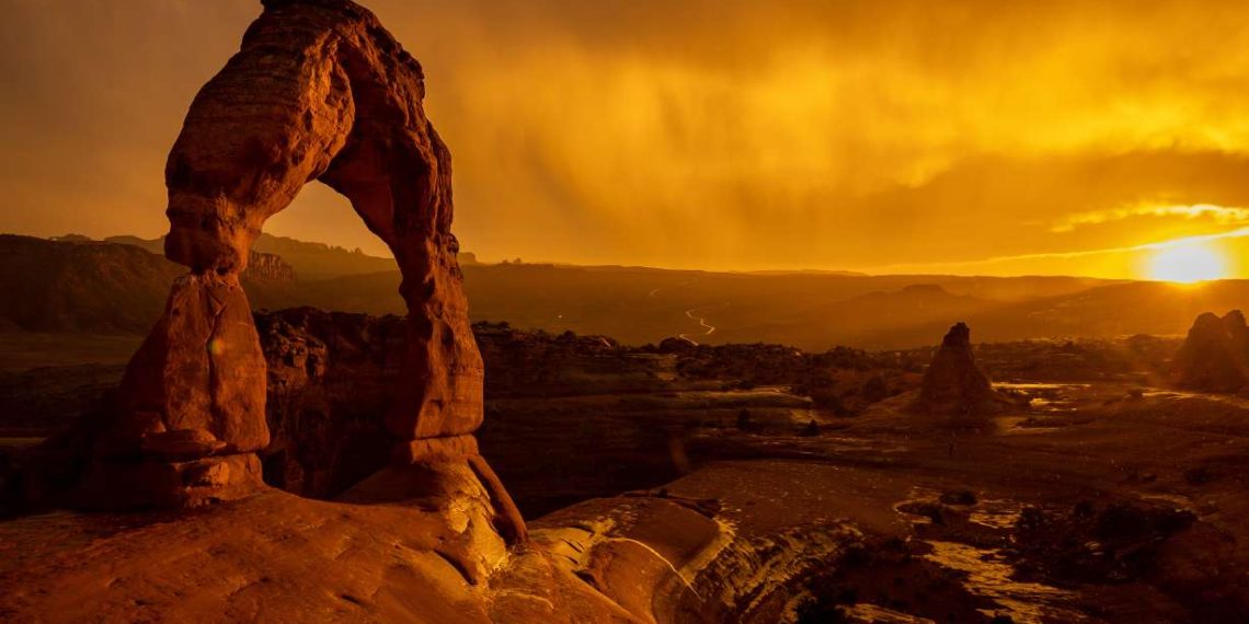The sun sets as a rainstorm blows over Delicate Arch in Arches National Park near Moab on Sept. 18, 2021. While visitation at U.S. national parks hit record highs in 2021, travel and hospitality companies and associations both inside and outside of the United States aren't happy with the National Park Service's reservation systems.