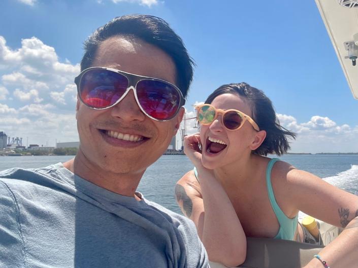 two people with sunglasses smiling on a boat