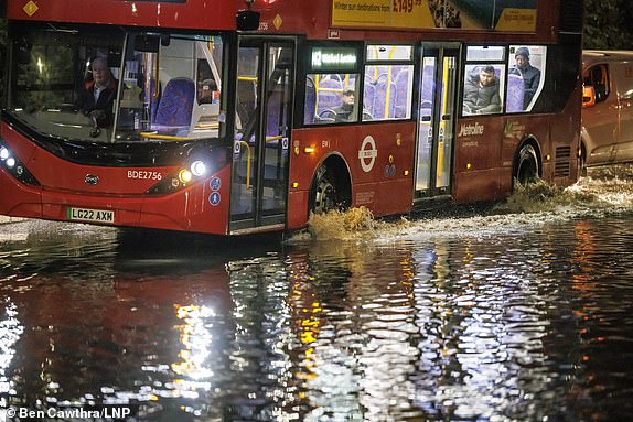 © Licensed to London News Pictures. 20/10/2023. London, UK. A bus ploughs through flood water at Brent Cross in north London, caused by heavy rain over night. A 'risk to life' warning has been issued by the Met Office, as storm Babet continues to bring wet and windy weather conditions to large parts of the UK. Photo credit: Ben Cawthra/LNP