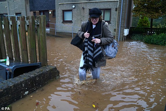 A woman walks through flood water in Brechin, Scotland, as Storm Babet batters the country. Flood warnings are in place in Scotland, as well as parts of northern England and the Midlands. Thousands were left without power and facing flooding from "unprecedented" amounts of rain in east Scotland, while Babet is set to spread into northern and eastern England on Friday. Picture date: Friday October 20, 2023. PA Photo. See PA story WEATHER Babet. Photo credit should read: Andrew Milligan/PA Wire