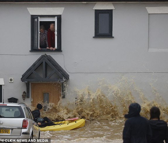 20 October 2023.Storm Badet has sealed of all the roads leading out of a little Suffolk village called Debenham.Farmers in there Tractors are helping stranded cars and people get to safety.The waves can been seen crashing against a couples home as they look from the window above as a woman on a canoe is bashed against there house.Credit: CLICK NEWS AND MEDIA   Ref: Ralph newCLICK NEWS AND MEDIA - PICTURES@CLICKNEWSANDMEDIA.COM - 07774 321240 - STANDARD SPACE RATES APPLY