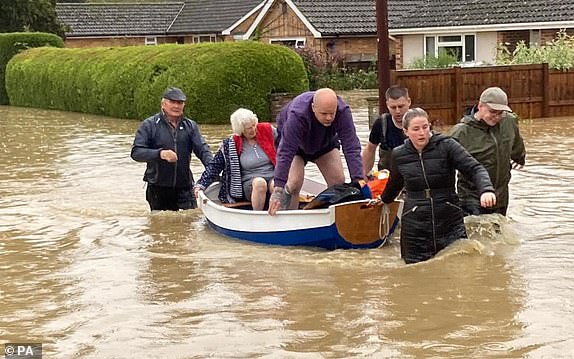 BEST QUALITY AVAILABLEHandout photo of Simon O'Brien (left) using his homemade boat, which he built for his grandchildren, to rescue elderly residents from their home in the village of Debenham, Suffolk, where people were cut off by flood water during Storm Babet. Picture date: Friday October 20, 2023. PA Photo. See PA story WEATHER Babet. Photo credit should read: Mary Scott/PA Wire NOTE TO EDITORS: This handout photo may only be used for editorial reporting purposes for the contemporaneous illustration of events, things or the people in the image or facts mentioned in the caption. Reuse of the picture may require further permission from the copyright holder.