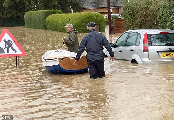 BEST QUALITY AVAILABLEHandout photo of Simon O'Brien (right) using his homemade boat, which he built for his grandchildren, to rescue elderly residents from their home in the village of Debenham, Suffolk, where people were cut off by flood water during Storm Babet. Picture date: Friday October 20, 2023. PA Photo. See PA story WEATHER Babet. Photo credit should read: Mary Scott/PA Wire NOTE TO EDITORS: This handout photo may only be used for editorial reporting purposes for the contemporaneous illustration of events, things or the people in the image or facts mentioned in the caption. Reuse of the picture may require further permission from the copyright holder.