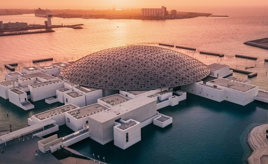 A landscape view of the Louvre Abu Dhabi Museum showcasing the iconic Rain of Light dome across the - Travel News, Insights & Resources.