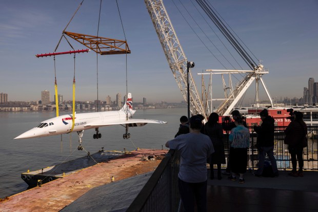 People watch a retired British Airways Concorde supersonic aircraft is lifted by a crane at the Intrepid Museum, Thursday, March 14, 2024, in New York. (AP Photo/Yuki Iwamura)
