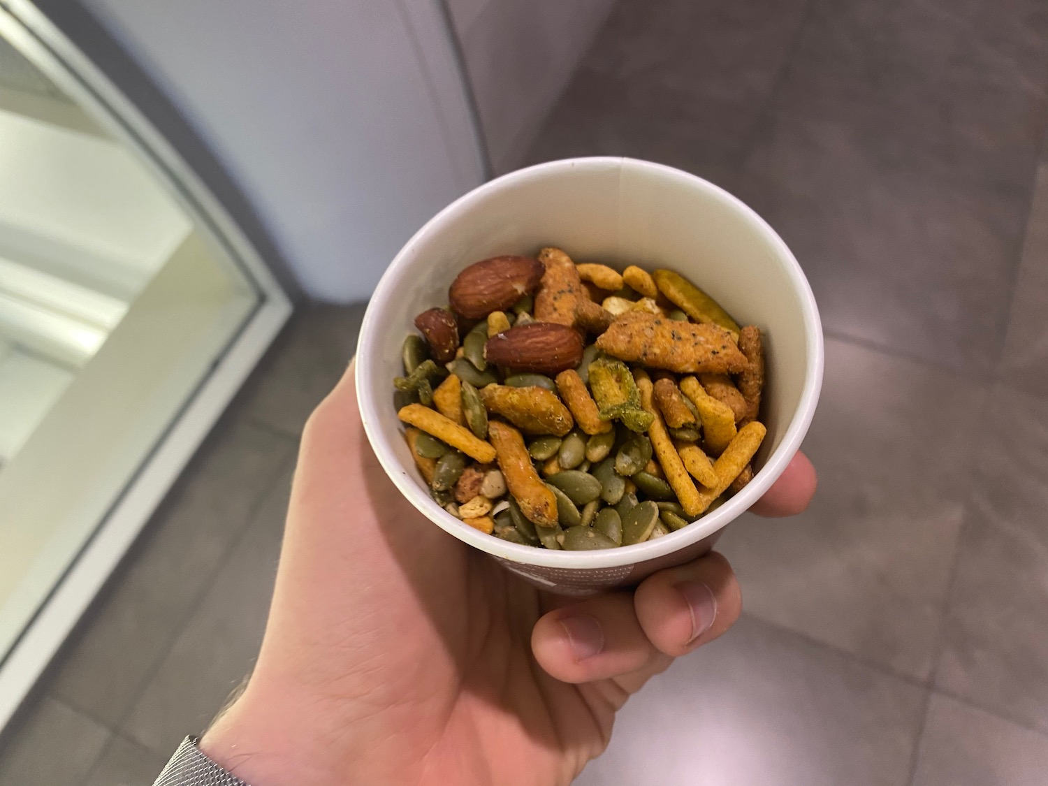 a hand holding a cup of mixed nuts and seeds
