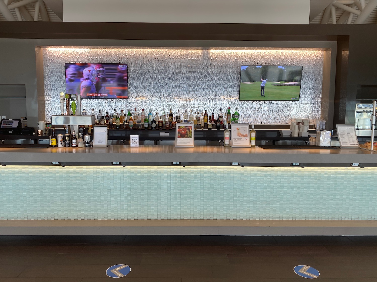a bar with bottles and tvs on the wall