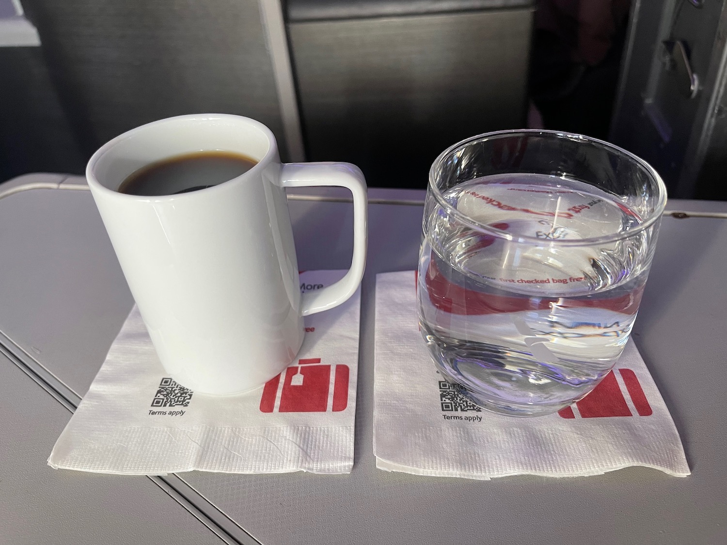 a cup of coffee and a glass of water on napkins