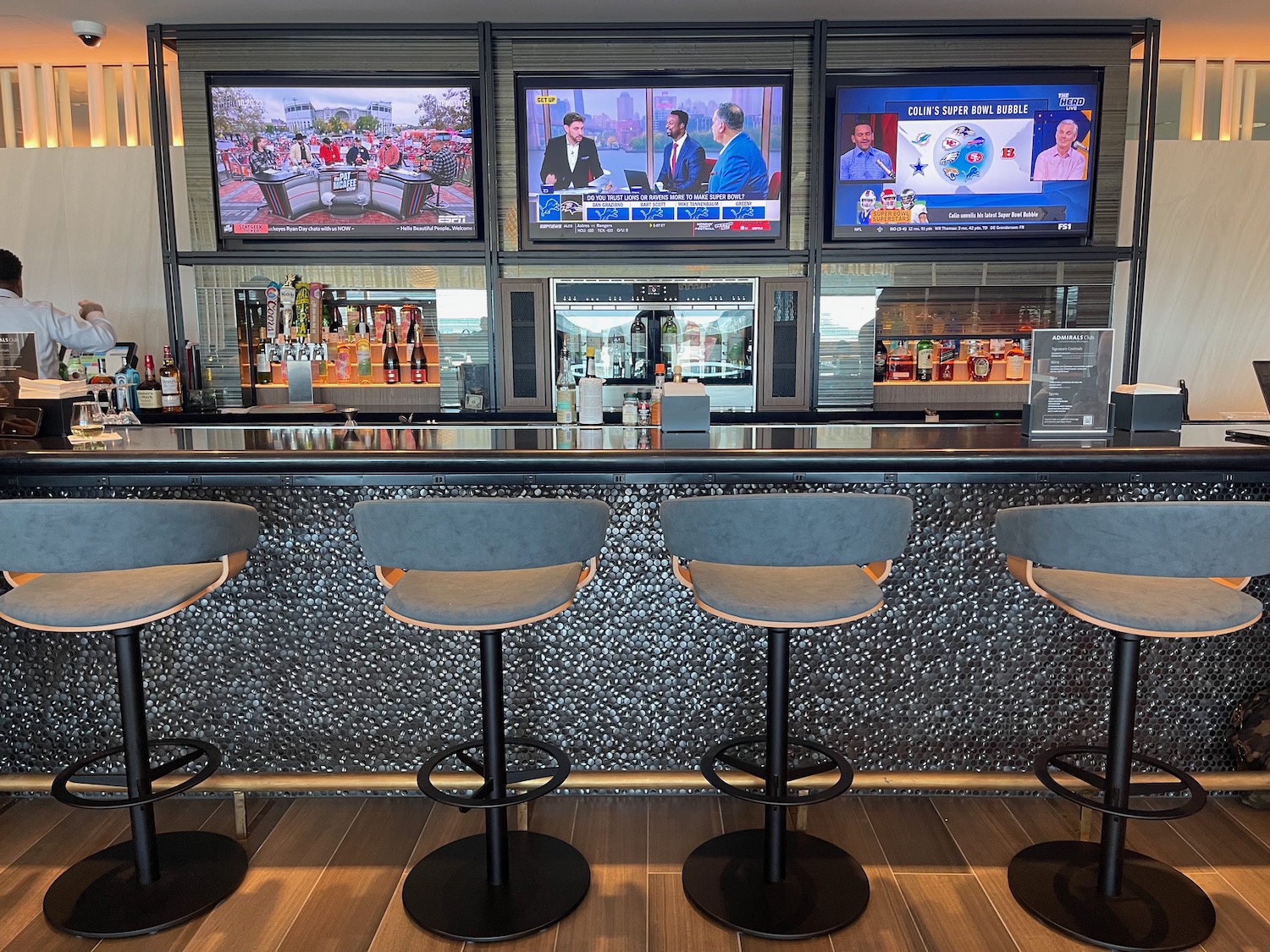 a bar with a row of chairs and televisions