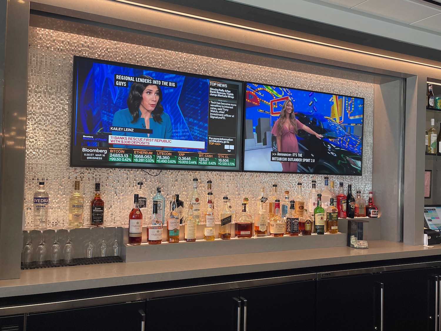 a bar with a television and a row of bottles