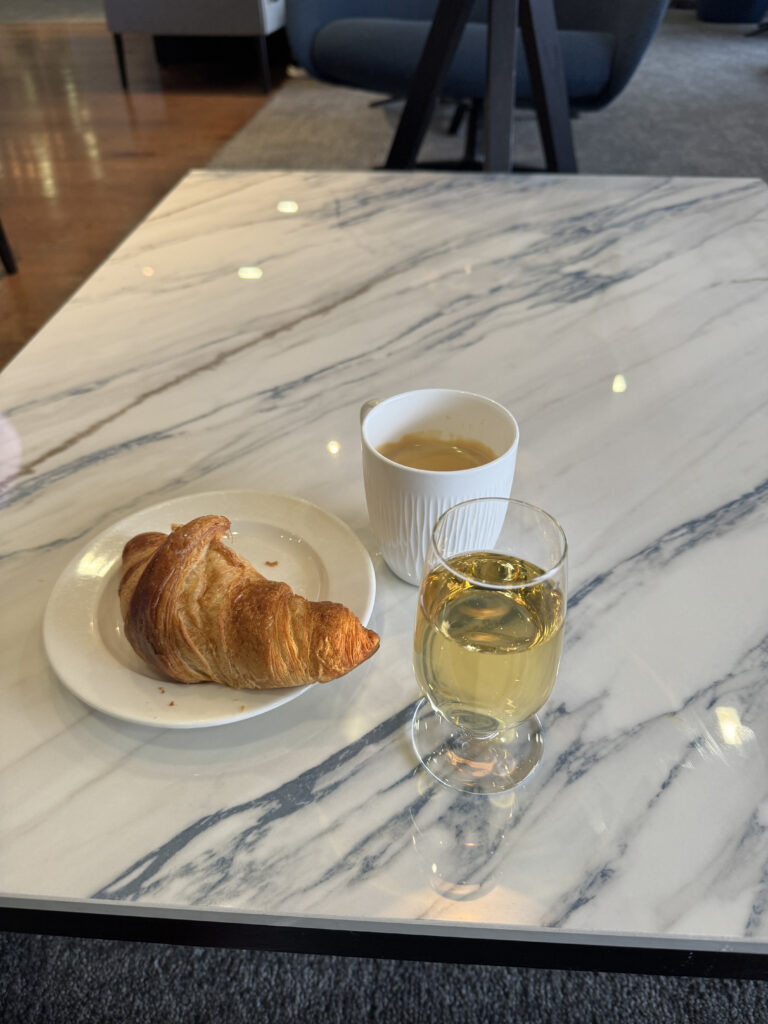 A glass of Champagne next to a croissant on a marble surface. 
