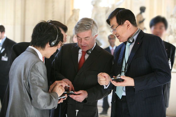 Cho, right, listens to the Korean language audio guide at the Louvre Museum in Paris, France, after he signed a deal to provide Korean language services at the company in 2008. [HANJIN GROUP]