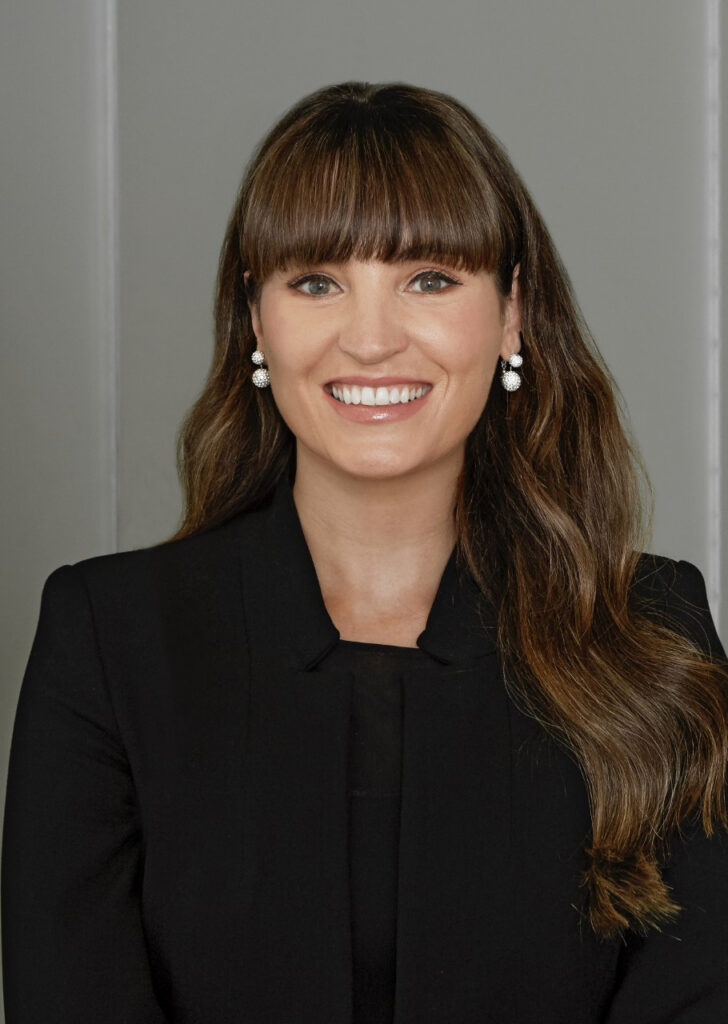 Yvonne Moynihan, Corporate and ESG Officer, Wizz Air Group, is pictured here smiling for a classic headshot. She is wearing earrings and a black suit.