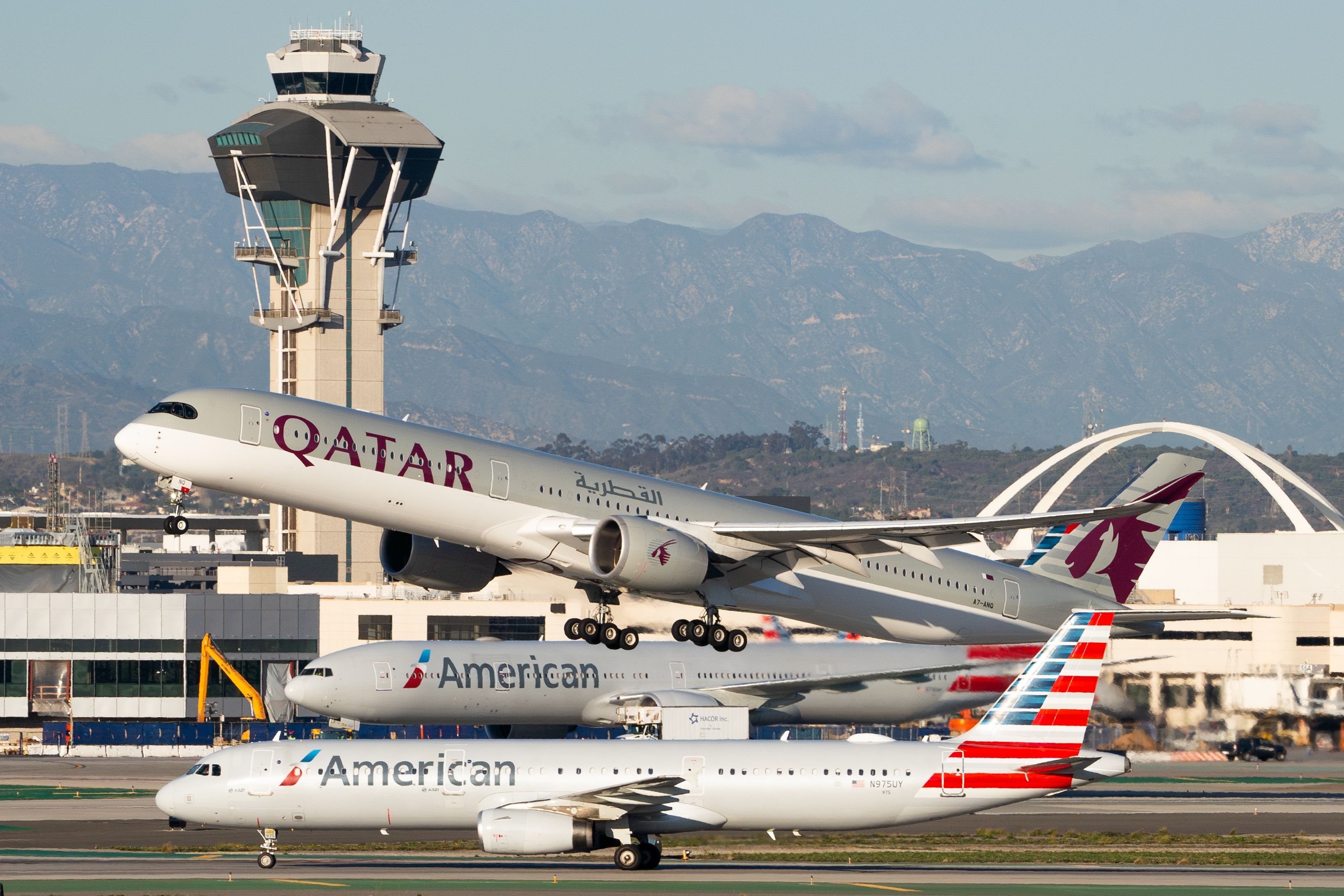 A Qatar Airlines Airbus A350 taking off in between two American Airlines jets. They are all part of the oneworld alliance